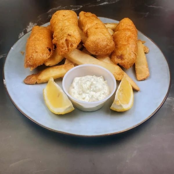 Golden-brown fish and chips with tartar sauce and lemon wedges on a light blue plate.