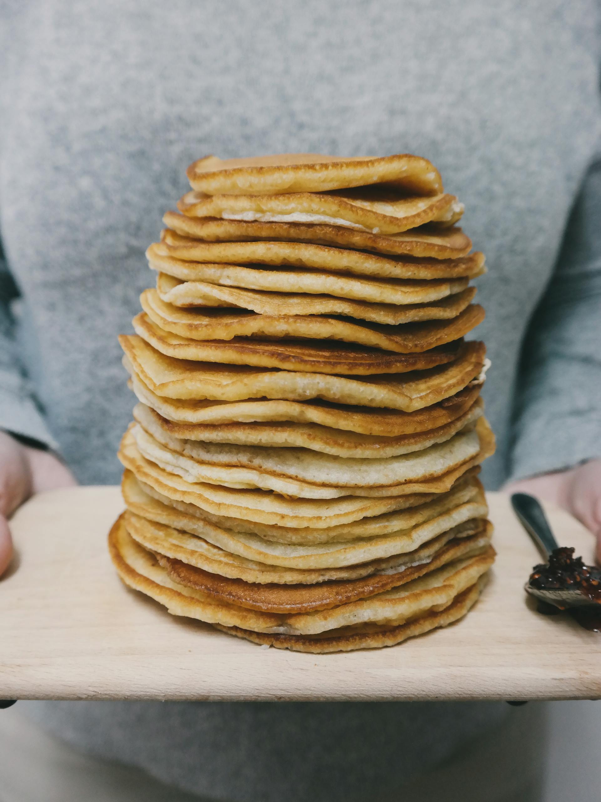 A towering stack of delicious homemade pancakes served on a wooden board. Perfect for breakfast.